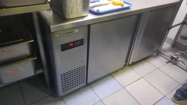 Mesón refrigerado de acero inoxidable con control digital en una cocina comercial